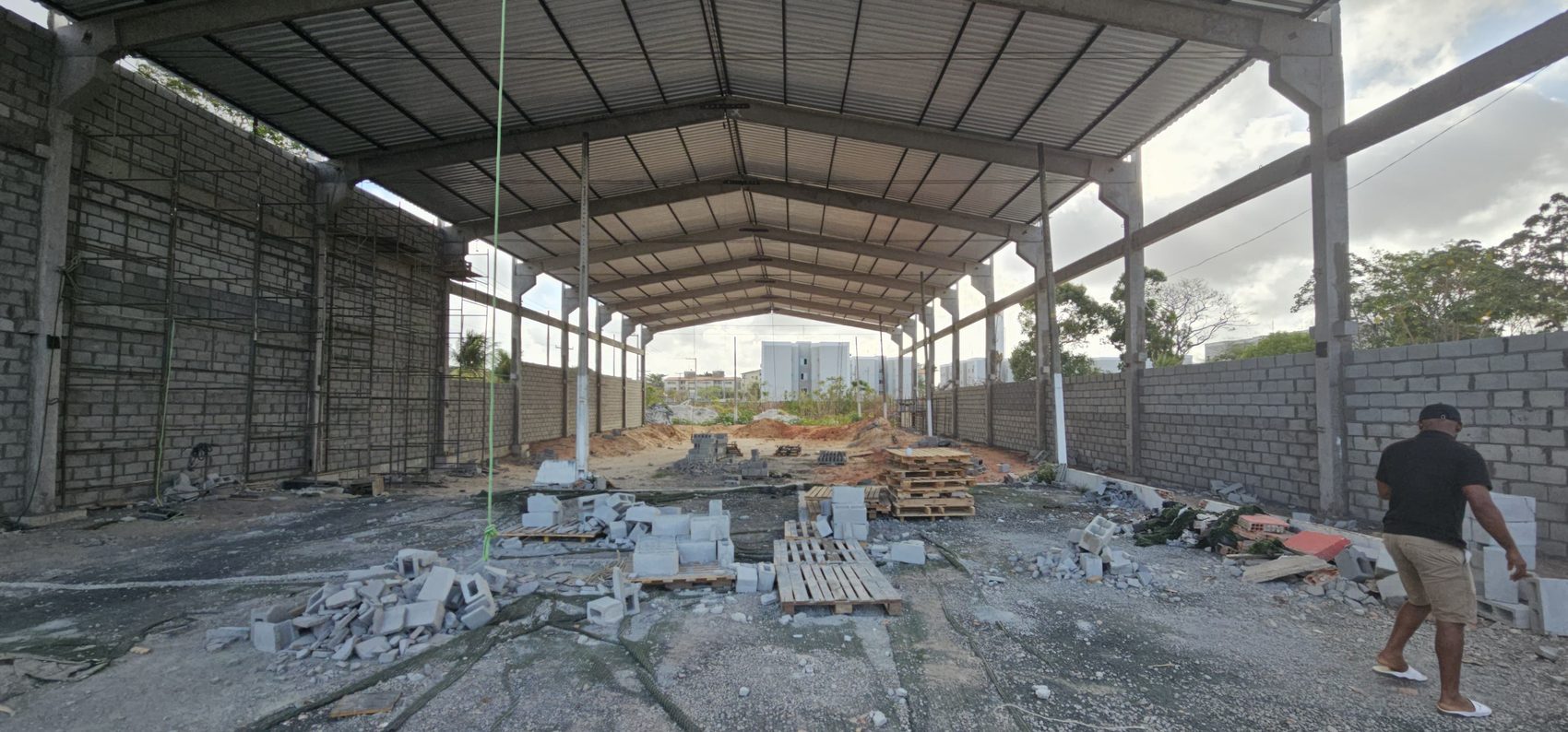 Interior do galpão pré-fabricado com cobertura concluída e fechamento em alvenaria