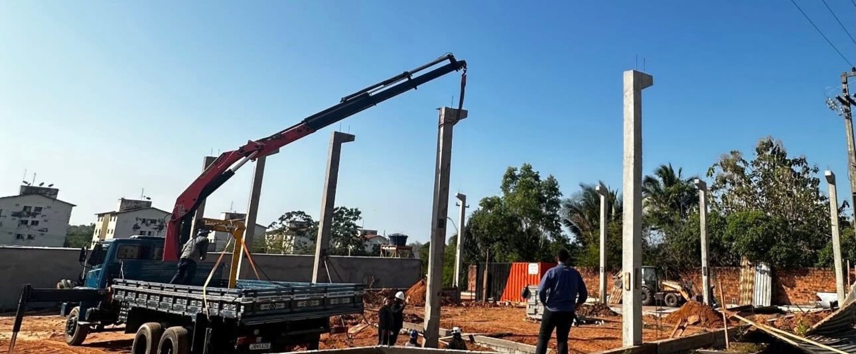 Caminhão munck içando um pilar pré-fabricado de concreto para posicionamento na obra