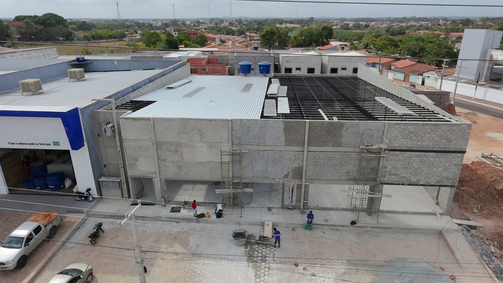 Vista aérea de obra comercial executada em estrutura pré-fabricada, com laje e cobertura em andamento
